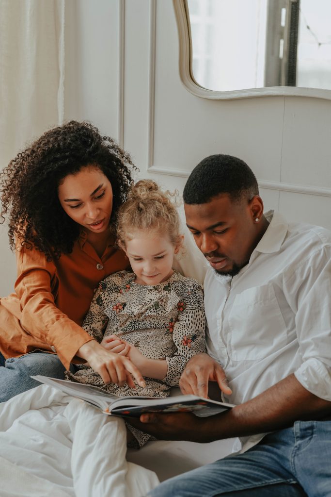 Foster parents reading a book with a young child at home